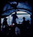 Group of people, including expedition members, riding in a barge on the Okavango River