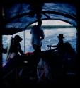 Group of people, including expedition members, riding in a barge on the Okavango River