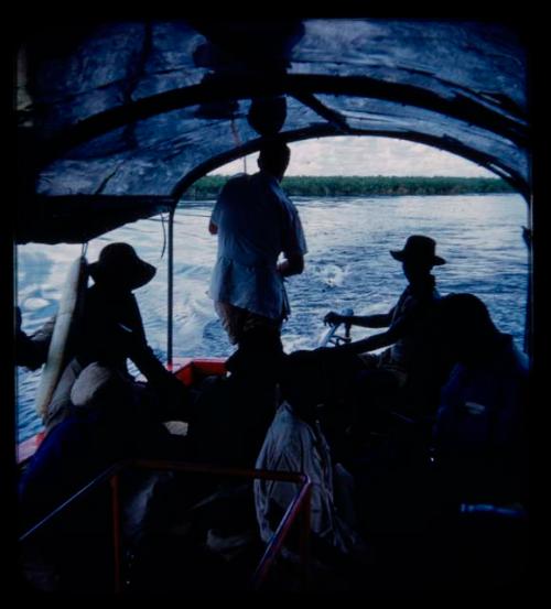 Group of people, including expedition members, riding in a barge on the Kavango River