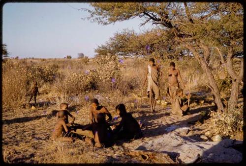 Group of people sitting together, women walking in the background