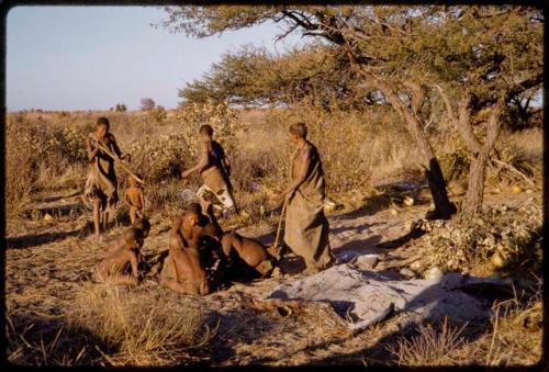 Group of people sitting together, women walking in the background