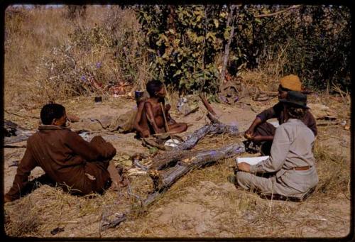 Oukwane sitting with Ledimo, /Gishay, and Lorna Marshall with a notebook