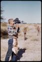 John Marshall wearing skin apron and filming during target practice