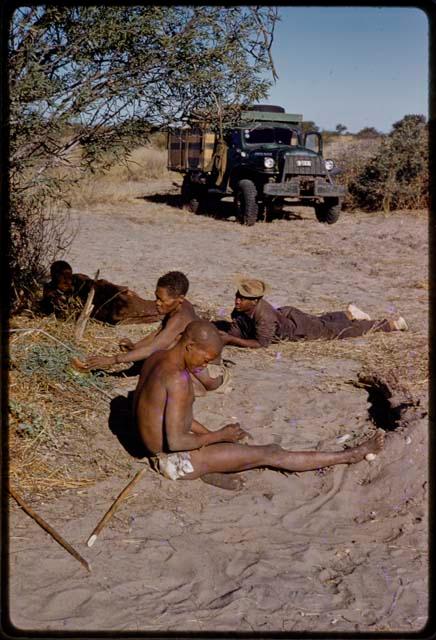 Gai, Oukwane, Kernel Ledimo, and another person lying on the ground, expedition truck in the background