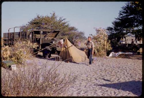 John Marshall walking, holding a gun at expedition camp