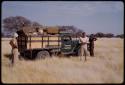 Expedition members standing by expedition truck parked in a field