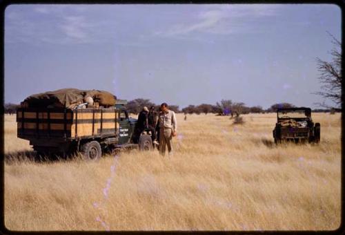 Expedition members standing by expedition trucks parked in a field