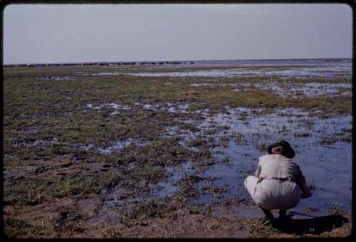 Lorna Marshall washing hands in Lake Ngami, from behind