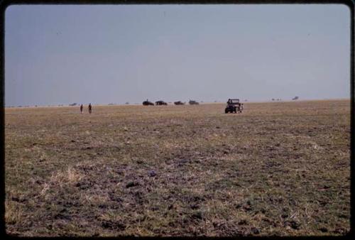 Trucks on flat plain, in the distance