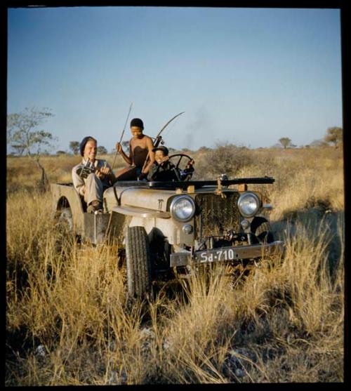 Expedition: //Ao sitting in the back of the expedition Jeep holding hunting equipment, with Ngani driving and John Marshall sitting in the front holding his film camera