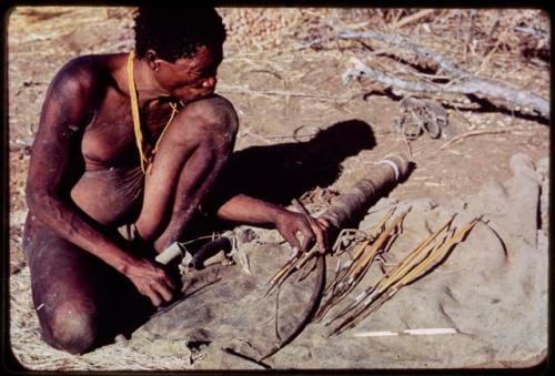 Arrow: "Old Gau" sitting, with his quiver and its contents on the ground next to him, including arrows, two bone points and a horn