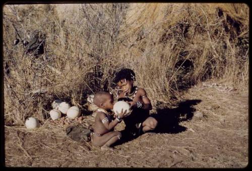 Children, Eating: N!ai giving a drink of water from an ostrich eggshell to /Gaishay, her half-brother