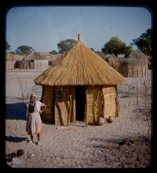 Woman standing in front of a hut