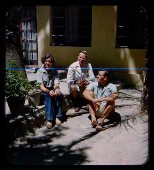 Brian Ensilin sitting with his sister and another man on the steps of his house