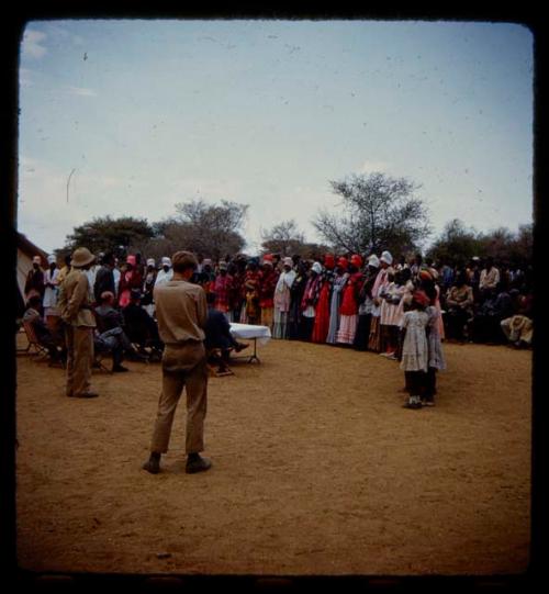 Omajetti indaba, group of women standing around men sitting next to a table