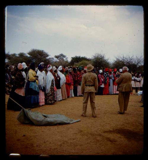 Omajetti indaba, large group of women and girls standing, with a man in a uniform and a man in a suit standing in front of them