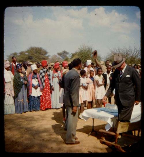 Omajetti indaba, large group of people standing, with two men in suits standing next to a table in front of them