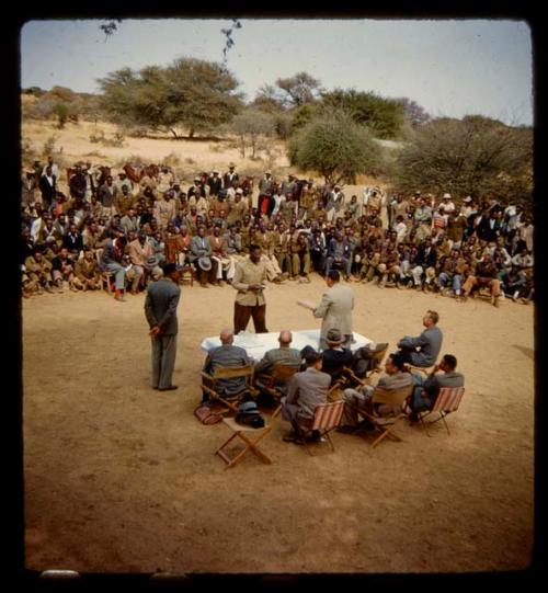 Omajetti indaba, large group of people sitting and standing around a group of men sitting next to a table