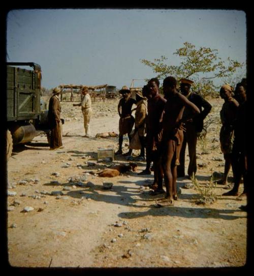 Group of people standing, with Edward and William Hartley standing next to an expedition truck near them