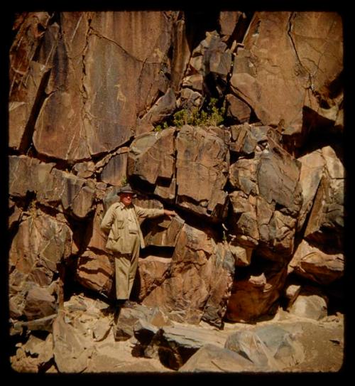 Merl La Voy standing next to petroglyphs of a rhino and human feet