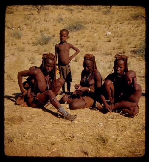 Women and children sitting, with a child standing next to them