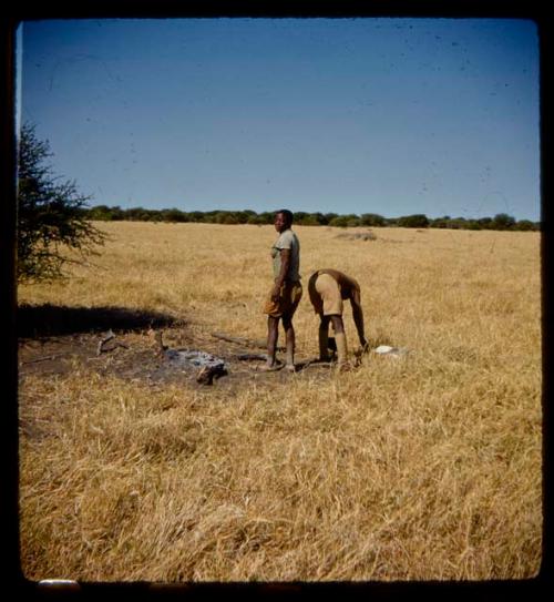 Expedition member leaning over, with another standing next to him