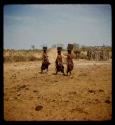 Three women walking, carrying buckets on their heads