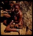 Woman sitting next to a hut, close-up