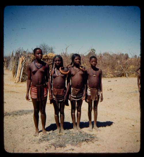 Group of women and girls standing, two wearing horns indicating eligibility for marriage