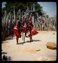 Four of Nehemiah's wives pounding something in holes in the ground with long poles