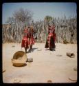 Four of Nehemiah's wives pounding something in holes in the ground with long poles