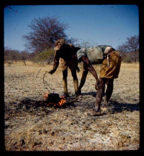 Two men, one a soldier guide, cooking something in a pot on a fire