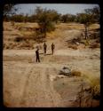 John Marshall and two other expedition members walking on a road, distant view