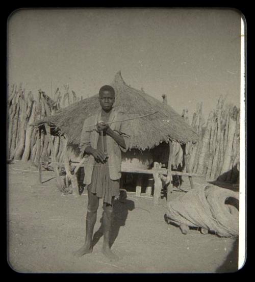 Man standing inside a kraal, holding a bow