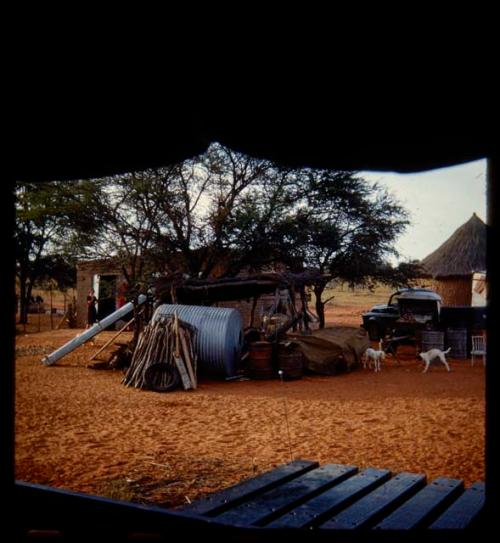 Farm equipment, with a building and a hut in the background