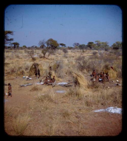 People sitting in front of skerms, with a child walking near them