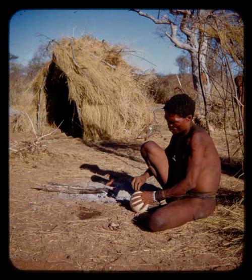 "Gao Medicine" sitting, holding an ostrich eggshell, with a skerm in the background