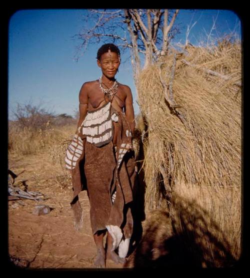 Headwife of a band at Gautscha wearing a decorated kaross, standing next to a skerm