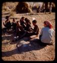 Group of boys sitting and making plasticene models, with Elizabeth Marshall Thomas watching