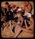 Boys making plasticene models of animals, with a man cutting up meat in the background