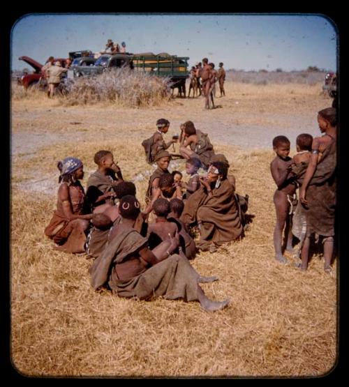 People sitting and standing, with expedition trucks in the background