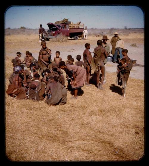 People sitting and standing, with expedition trucks in the background