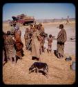 People standing, with a dog near them, expedition truck in the background