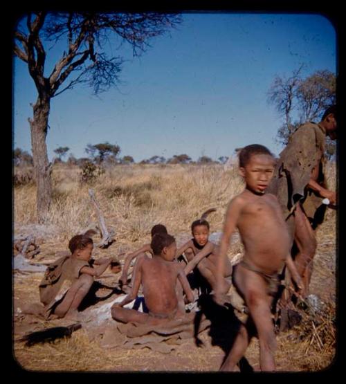 People sitting and standing, including /Gishay (younger son of "Old Gau"), /Gao (older son of "Old Gau"), "Lame ≠Gao", Tsamgao (≠Toma's son) and /Qui (//Kushay's husband)