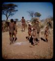 /Gishay, Tsamgao, N!aishi, N!ai, N/ani and /Gaishay dancing, with "Gao Medicine" standing in the background