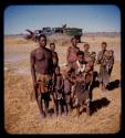 Thoria standing with his wife and children in a group of people, with expedition trucks in the background