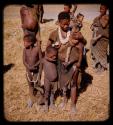 Woman carrying a baby, standing with her children, with other people standing behind her