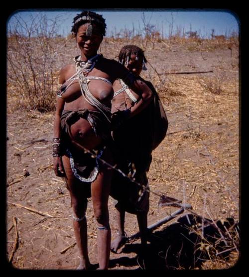 Woman standing, with a child standing behind her