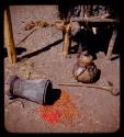 Beans on the ground next to a mortar, a gourd and a stool