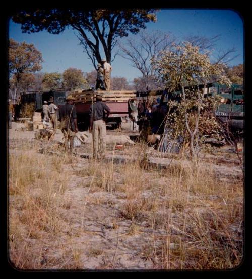 Group of people and expedition members standing next to trucks